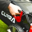 User adjusting the single-lever cutting height control on the Cobra MX484SPCE petrol lawnmower