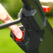Close-up of a user pressing the electric push-button start on the Cobra MX484SPCE lawnmower handle