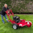 A man posing next to the fully-assembled stump grinder.